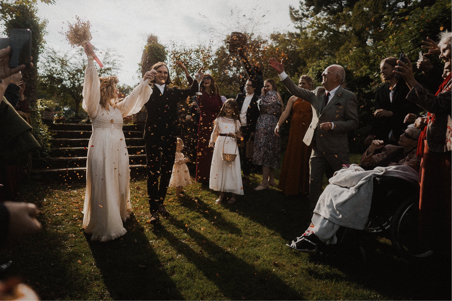 Wedding couple tossing confetti in joyful celebration.